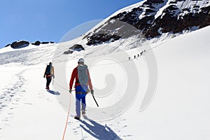 Rope team mountaineering with crampons on glacier Sexegertenferner towards Sexegertenspitze and mountain snow panorama with blue