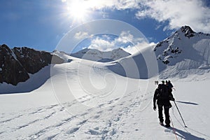 Rope team mountaineering with crampons on glacier Taschachferner towards Wildspitze and mountain snow panorama with blue sky in