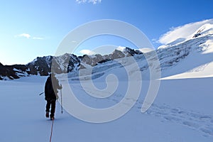 Rope team mountaineering with crampons on glacier Taschachferner towards Wildspitze and mountain snow panorama with blue sky in