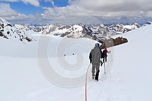 Rope team mountaineering with crampons and people skiing on glacier Taschachferner from Wildspitze down and mountain snow panorama