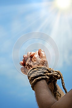 Rope tied hands on sky background