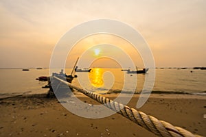 Rope tied small fishing boat at the beach in sunset