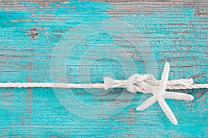 Rope tied to a starfish on turquoise wooden background