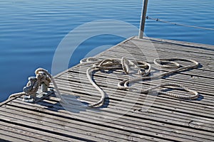 Rope tied up on a bitt on wooden dock