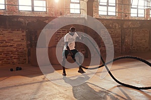 Rope workout. Sport man doing battle ropes exercise at gym