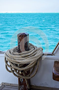 Rope is wound on mooring post of yacht. View on background of blue sea. Copy space. Close-up.