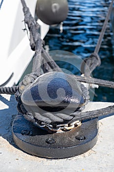 Ropes on black mooring bollard, marina Floisvou, Greece. Vertical