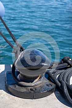 Ropes on black mooring bollard, marina Floisvou, Greece. Vertical