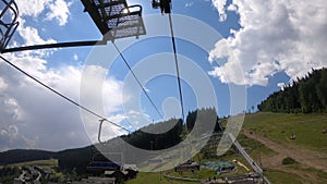 Ropeway with people movement in forest in mountains on sunny day.