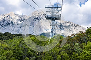 Ropeway tower against cloudy sky, forest and AI-Petri mountain in Crimea