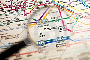 Roppongi Tokyo metro station on a printed metro map under a magnifier lens