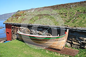 Rorbu with grass on the roof and old boat