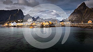 Rorbu houses of Sakrisoy fishing village on a cloudy day with mountains in the background