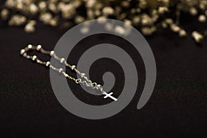 Rosary beads with blurred white small flowers, black background