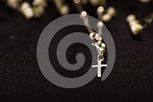 Rosary beads with blurred white small flowers, black background