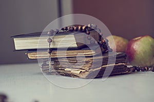 The rosary beads on Catholic Church liturgy books and apples behind them.