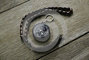 Rosary beads and compass on wooden background