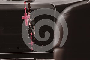 Rosary beads hanging in the mirror in the car