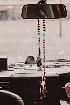 Rosary beads hanging in the mirror in the car