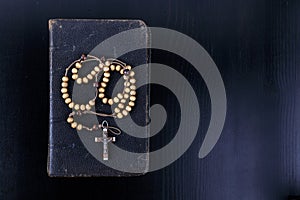 Rosary beads and prayer book on dark background photo