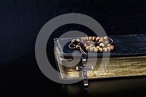 Rosary beads and prayer book on dark background photo