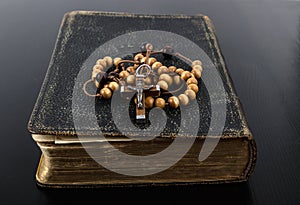 Rosary beads and prayer book on dark background photo