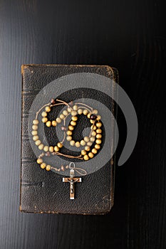 Rosary beads and prayer book on dark background