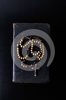 Rosary beads and prayer book on dark background