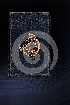 Rosary beads and prayer book on dark background photo