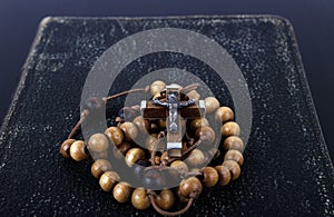 Rosary beads and prayer book on dark background photo