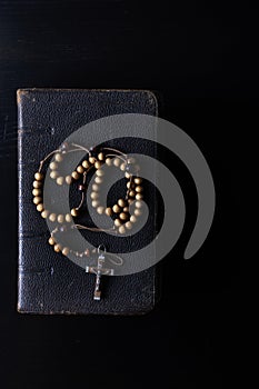 Rosary beads and prayer book on dark background photo