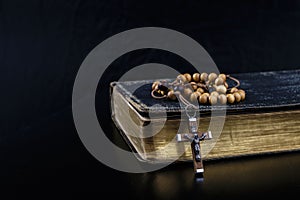 Rosary beads and prayer book on dark background photo