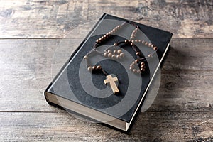 Rosary catholic cross on Holy Bible on wood photo