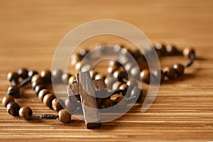 The Rosary. Close up of wooden rosary beads with Jesus Christ holy cross crucifix on the table in brown color background.