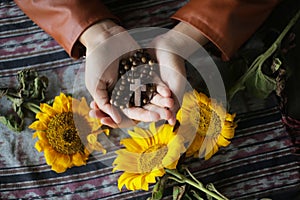 Rosary in hand. Young junior lady holding rosary with open hand. Female hands holding a rosary with Jesus Christ Cross Crucifix.