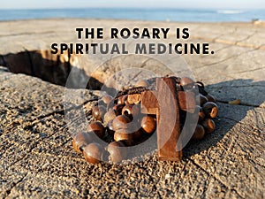 Rosary inspirational quote - The Rosary is spiritual medicine. With background of wooden rosary on wood, with holy cross of Jesus.