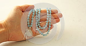 Rosary mala 108 beads from natural stones Aquamarine lie in girl`s hand. Author`s jewelry from natural stones, Buddhism, matra,