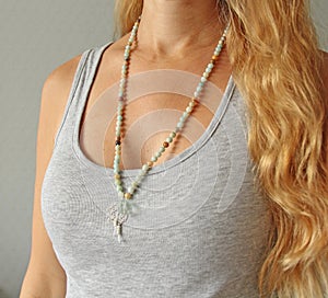 Rosary mala 108 beads from natural stones mint amazonite are worn on a girl in a grey shirt. Author`s jewelry from natural stones