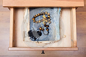 Rosary on old religious book in open drawer