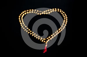 Rosary of sandalwood on a wooden table laid out in the form of a tree.