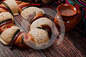 Rosca de reyes or Epiphany cake and clay mug of mexican hot chocolate on a wooden table in Mexico Latin America