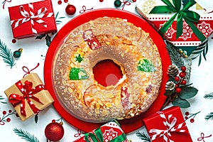 Roscon de reyes with cream and christmas ornaments on a red plate. Kings day concept spanish three kings cake.Typical spanish