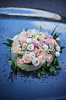 Rose bouquet on a car hood, with rain drops