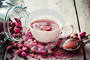 Rose buds tea, tea cup, strainer and glass jar with rosebuds