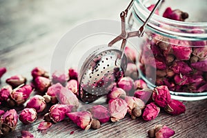 Rose buds tea, tea infuser and glass jar.