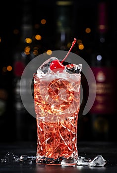 Rose with cherry, alcoholic cocktail drink with pink vermouth, amaretto liqueur, cherry juice, red cocktail cherry and ice, black