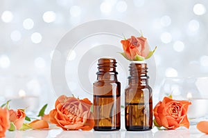 Rose essential oil bottles on white table with bokeh effect. Spa, aromatherapy, wellness, beauty background.