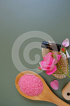Rose essential oil and cosmetics salt with rose extract. Glass bottles,rose flowers and cosmetics salt on green