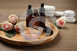 Rose essential oil and flowers on wooden table