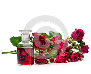 Rose essential oil in a glass bottle and flowers roses